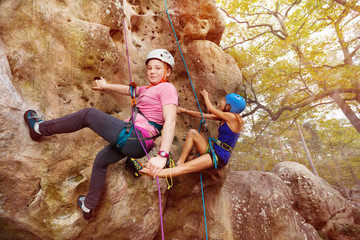 Young girl climbs a rock with female instructor