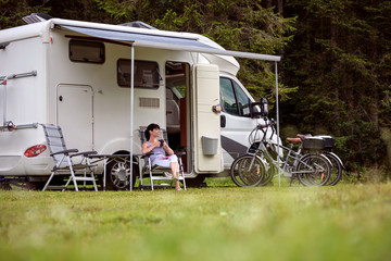 woman is standing with a mug of coffee near the camper rv.