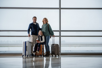 Full length portrait of glad parents and their daughter flying to another country. Copy space in right side