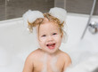 © Ermolaev Alexandr - Happy little cute girl bathes in a bath with foam and soap bubbles and  laughing