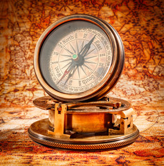 Vintage compass lies on an ancient world map.