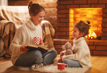 Sticker - family mother and child reading book on winter evening by fireplace.