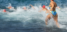 Group Triathlon Participants Running Into The Water For Swim Portion Of Race,splash Of Water And Athletes Running
