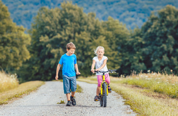 Poster - Kleiner Junge und Mädchen laufen und fahren Fahrrad auf einem Feldweg