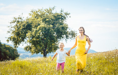 Poster - Mutter mit ihrer Tochter läuft über die Wiese