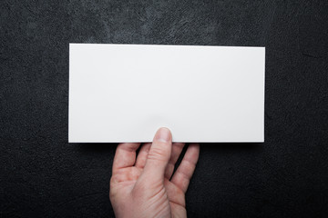 Mockup of a postal envelope in hand on a black background.