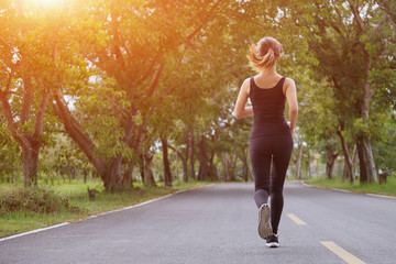 Wall Mural - Young fitness sport woman running on the road in the morning, Sun light flare , Selective focus.