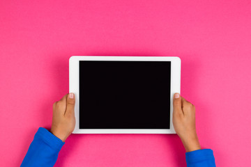 Wall Mural - Kid hands with tablet computer on pink background.