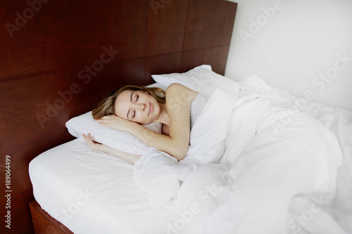 Plakat piękna kobieta spać w łóżku z białą pościelą w domu