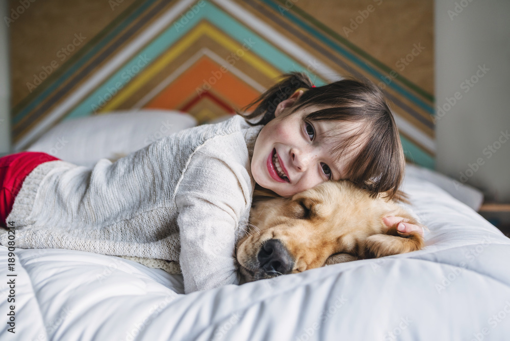 Girl lying on a bed with her golden retriever dog Stock Photo | Adobe Stock