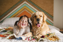 Portrait Of Young Girl Playing With Dog On A Bed