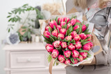 Fototapeta  - beautiful luxury bouquet of pink tulips flowers in woman hand. the work of the florist at a flower shop. cute lovely girl