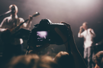 Canvas Print - Someone's dslr camera with the video record mode on a concert with the live view picture on a screen. Music band on a stage as an object of shooting