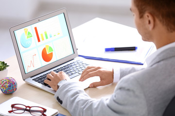 Marketing manager using laptop at table in office