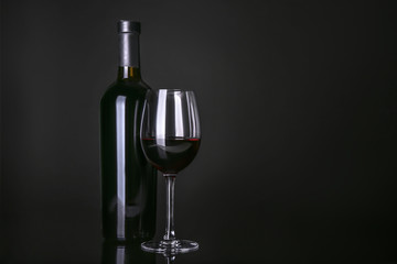 Wall Mural - Bottle and glass with red wine on black background