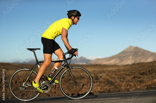 Cuadros en Lienzo Biking cyclist male athlete going uphill on open road training hard on bicycle outdoors at sunset