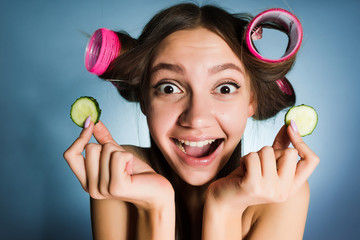 Poster - happy woman with curlers on her head holding cucumbers in her hands