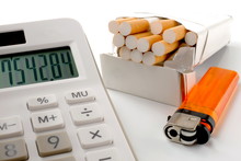 Closeup On Calculator With Digits On Display, Cigarette Pack And Lighter On White Background, Smoking Expenses Concept