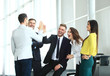 © opolja - Happy successful multiracial business team giving a high fives gesture as they laugh and cheer their success