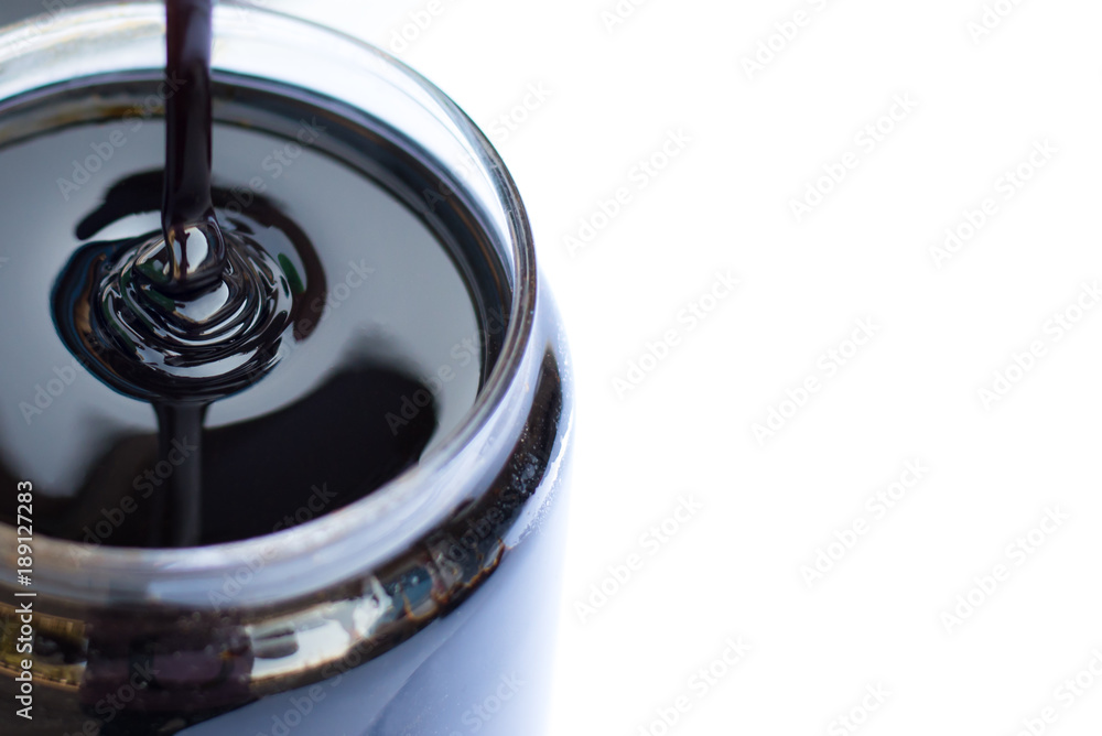 Molasses sugarcane on beaker isolate on white background. Droping ...
