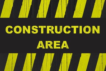 Construction area warning sign with yellow and black stripes painted over cracked wood. Concept image for construction sites meaning: do not enter the area, caution, danger