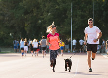 Young Couple Runnig With French Bulldog  At Sport Field