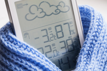 Wall Mural - Weather station device in the light blue knitted scarf on a light background. Closeup, selective focus