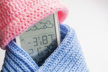 Wall Mural - Weather station device in the light blue knitted scarf and pink cap on a light background. Closeup, selective focus