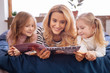 © Viacheslav Yakobchuk - Magazine. Good-looking gleeful blond mother and her little daughters smiling and reading a magazine while lying on bed