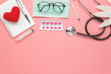 Wall Mural - Table top view aerial image of accessories healthcare & medical background concept.Red heart & stethoscope with copyspace on pink paper.Flat lay of idea for doctor treat patient in hospital.