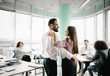 © Svyatoslav Lypynskyy - Male and female managers holding and looking at each other in office. Rest of team work on laptops.