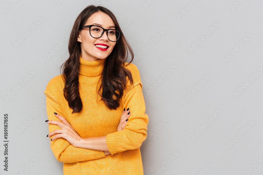 Smiling brunette woman in sweater and eyeglasses with crossed arms - obrazy, fototapety, plakaty 
