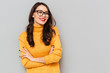 © Drobot Dean - Smiling brunette woman in sweater and eyeglasses with crossed arms