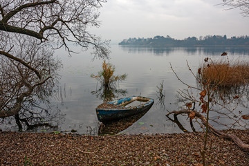 A boat abandoned on the shore of the lake, on a winter day