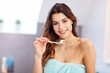 © Kalim - Young woman washing teeth in bathroom in the morning