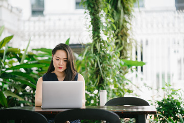 Portrait of young attractive businesswoman sitting and working at her laptop. She is looking at her screen and looks serious.