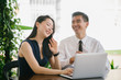 © Danon - Portrait of a young professional colleagues sitting outdoors at a table. They have a laptop and appear to be smiling and discussing with one another.