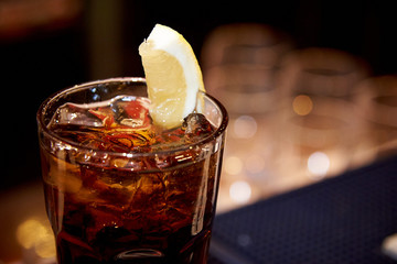 Ice tea with ice and lemon in a glass on a dark blurred background