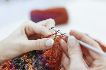 Wall Mural - close up of of a woman knitting a woolen scarf with brown colors