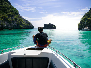 Poster - Man sit on prow of white sailing boat in Myanmar sea with mountain background.