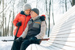 © beatleoff - Pretty senior couple sitting with nordic walking poles in winter park. Mature woman and old man resting outdoors. Healthy lifestyle concept.