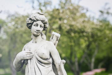 Old marble statue of Diana, goddess of hunt, moon, and nature, park. Sunny spring day, female hunter with bow and arrow.