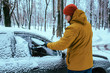 young man clean car after snow storm