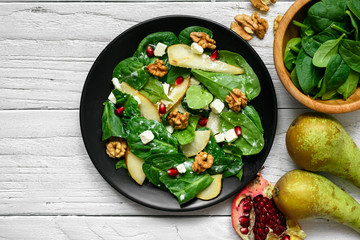 Poster - fresh spring salad with spinach leaves, pear, nuts, pomegranate and feta cheese in black plate