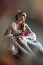 Young Woman Dressed In The Fashion Style Of Rococo With Vintage Red Hairstyle. Place For Text	