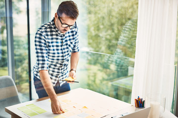 Wall Mural - Handsome designer working with notes from modern office