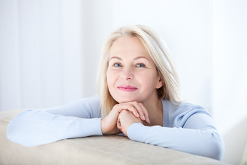 Active beautiful middle-aged woman smiling friendly and looking in camera. Woman's face closeup. Realistic images without retouching with their own imperfections. Selective focus.