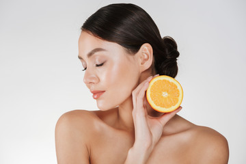 Poster - Close up image of charming woman with soft fresh skin holding juicy orange, having detox isolated over white background