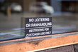 Sign for No Loitering or Panhandling on a window