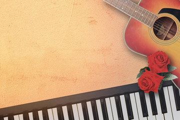 Spanish acoustic folk guitar and piano keyboard with beautiful two red rose symbol of love in the mood of ronantic soft light on texture italian floor background.